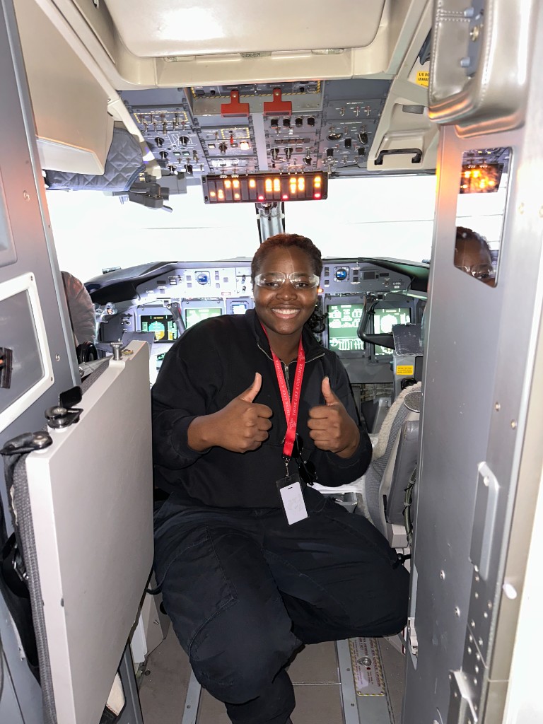 Portrait in an aircraft cockpit, giving a thumbs up